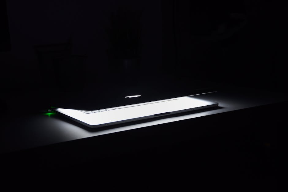 Minimal dark workspace with a glowing laptop